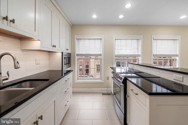 922 Fell St, Baltimore, MD 21231 - kitchen featuring white cabinets, a sink, stainless steel appliances, decorative backsplash, and baseboards