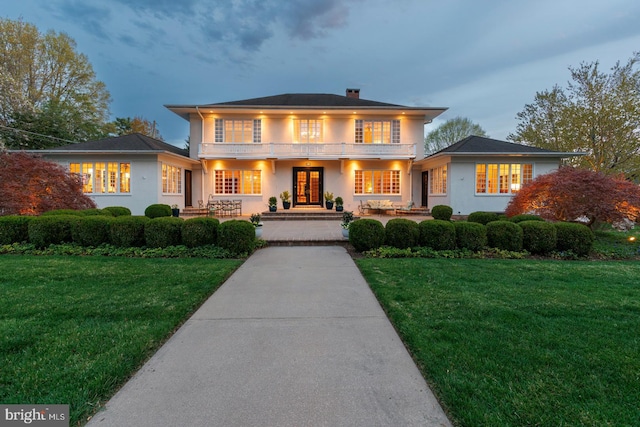 view of front of home featuring a chimney, stucco siding, and a front lawn