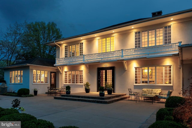 rear view of property with french doors, a patio area, stucco siding, and a balcony