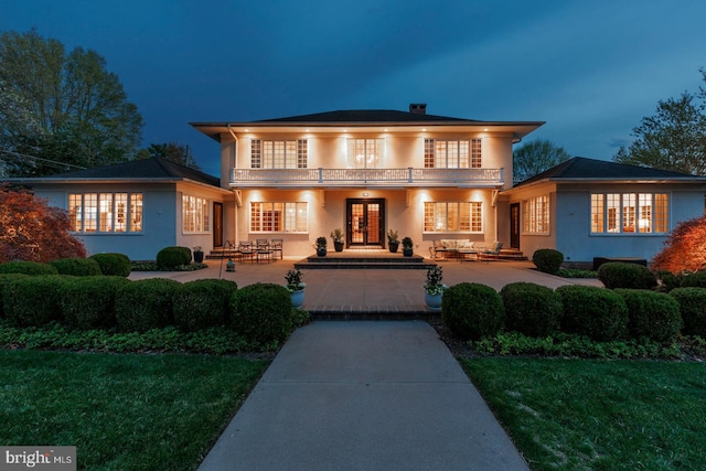 view of front facade with french doors, stucco siding, and a balcony