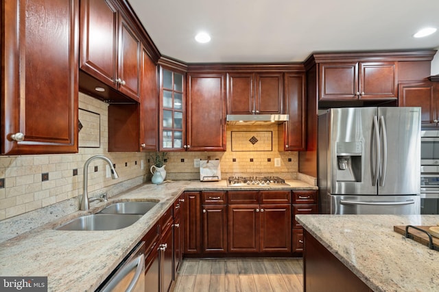 kitchen featuring dark brown cabinets, a sink, light wood-type flooring, stainless steel appliances, and under cabinet range hood