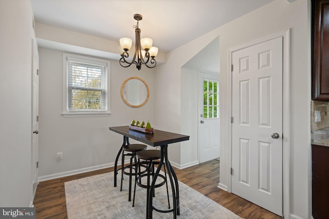 dining space featuring baseboards, a chandelier, and dark wood finished floors