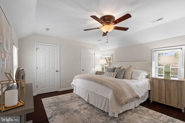 bedroom featuring dark wood finished floors, lofted ceiling, multiple windows, and visible vents