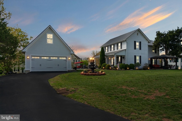traditional-style home with aphalt driveway, a front lawn, a gazebo, and a garage