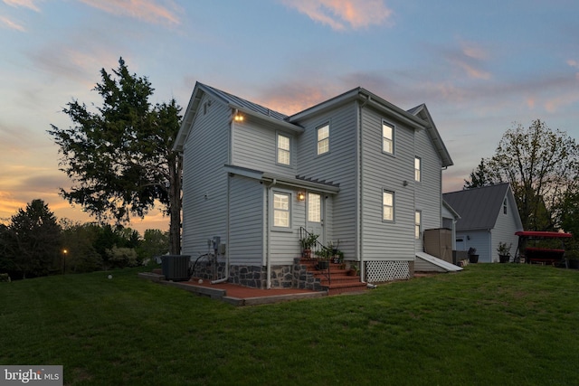 rear view of property featuring a yard and central air condition unit
