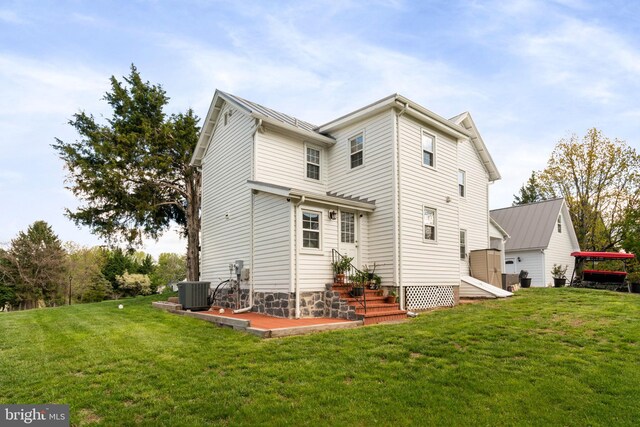 back of property with central air condition unit, a lawn, and entry steps