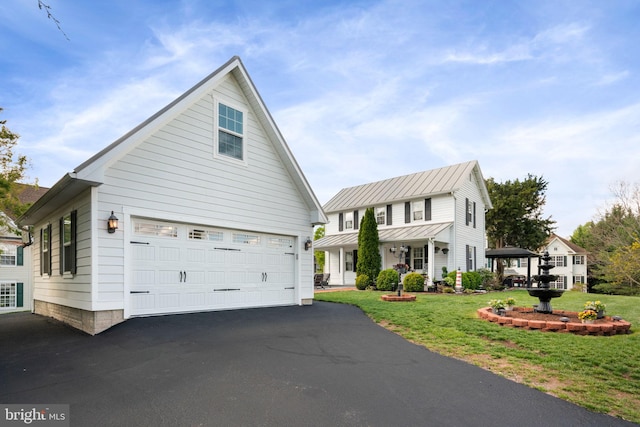 view of front of property featuring a standing seam roof, a front lawn, and aphalt driveway