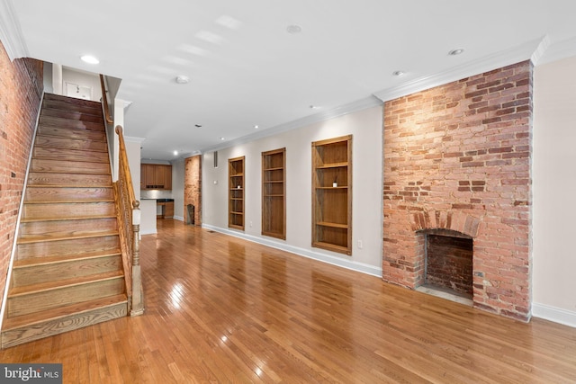 2415 Saint Paul St, Baltimore, MD 21218 - unfurnished living room featuring crown molding, light wood-type flooring, a fireplace, stairway, and built in features
