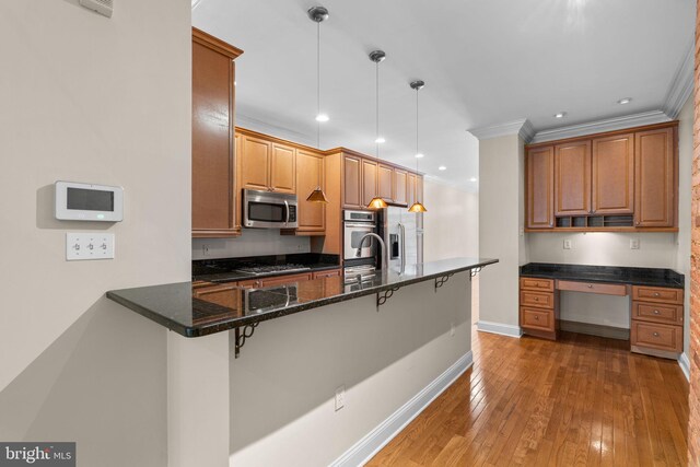 2415 Saint Paul St, Baltimore, MD 21218 - kitchen with stainless steel appliances, a kitchen bar, a peninsula, baseboards, and crown molding