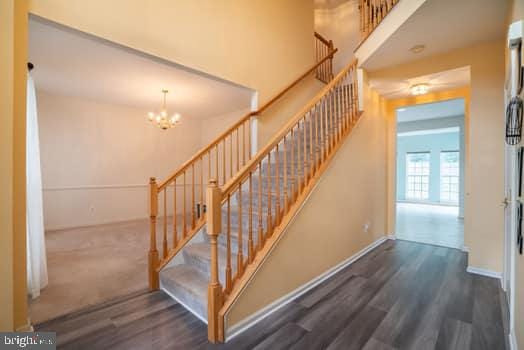 17661 Avenel Ln, Dumfries, VA 22026 - stairs featuring wood finished floors, baseboards, and a chandelier