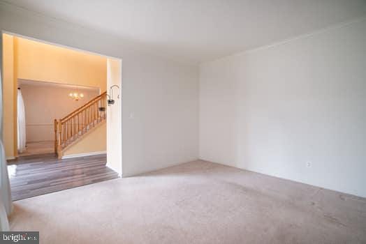 17661 Avenel Ln, Dumfries, VA 22026 - carpeted spare room with stairs and a chandelier