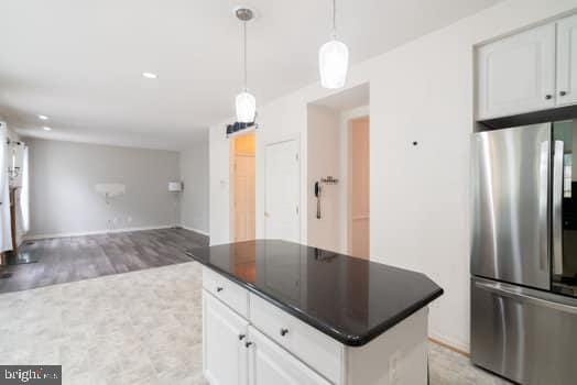 17661 Avenel Ln, Dumfries, VA 22026 - kitchen featuring freestanding refrigerator, dark countertops, a center island, white cabinets, and open floor plan