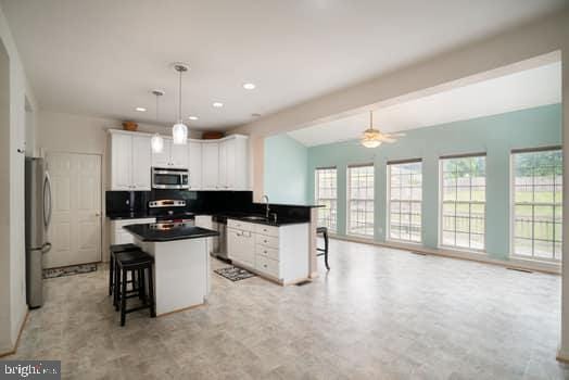 17661 Avenel Ln, Dumfries, VA 22026 - kitchen featuring stainless steel appliances, a sink, a kitchen bar, dark countertops, and open floor plan