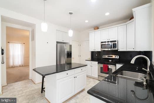 17661 Avenel Ln, Dumfries, VA 22026 - kitchen with stainless steel appliances, a sink, dark countertops, white cabinetry, and recessed lighting