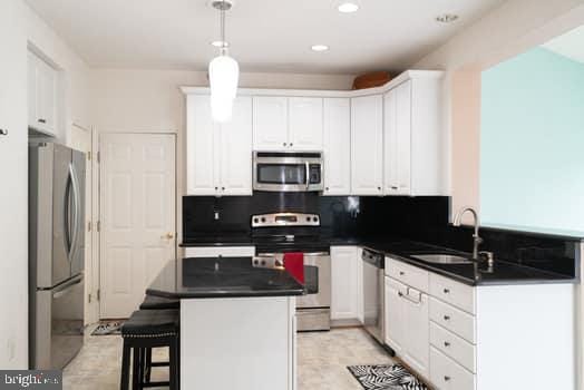 17661 Avenel Ln, Dumfries, VA 22026 - kitchen with stainless steel appliances, a sink, dark countertops, white cabinetry, and recessed lighting