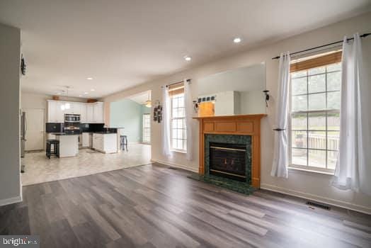 17661 Avenel Ln, Dumfries, VA 22026 - unfurnished living room with healthy amount of natural light, dark wood finished floors, a glass covered fireplace, baseboards, and recessed lighting