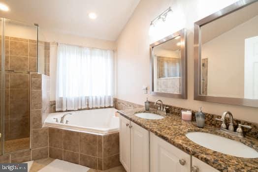 17661 Avenel Ln, Dumfries, VA 22026 - bathroom featuring a bath, double vanity, lofted ceiling, and a tile shower