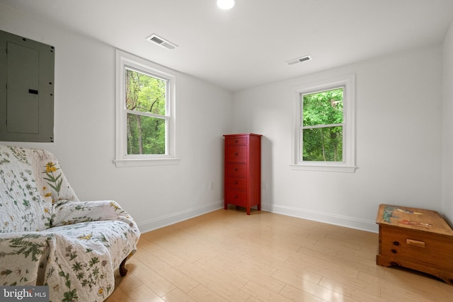living area featuring electric panel, plenty of natural light, and baseboards