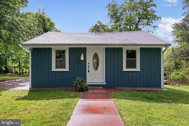 bungalow with a front yard and a shingled roof