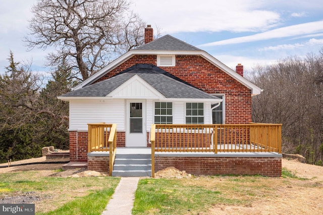 bungalow-style house with a chimney, a shingled roof, covered porch, and brick siding