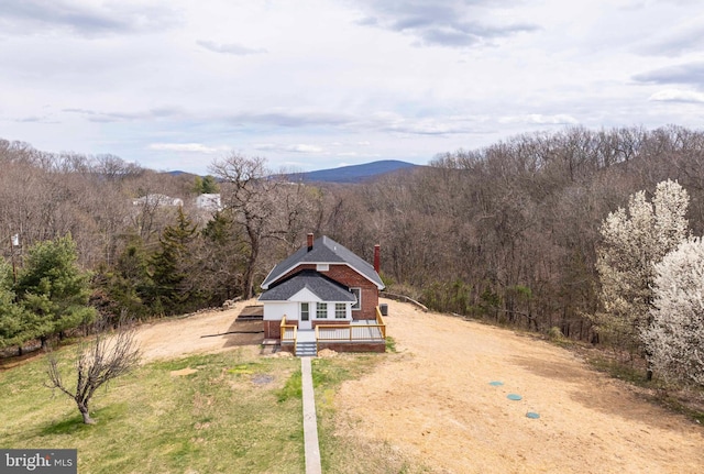 drone / aerial view featuring a wooded view and a mountain view