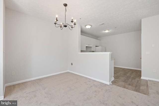 interior space with baseboards, visible vents, a textured ceiling, and a chandelier