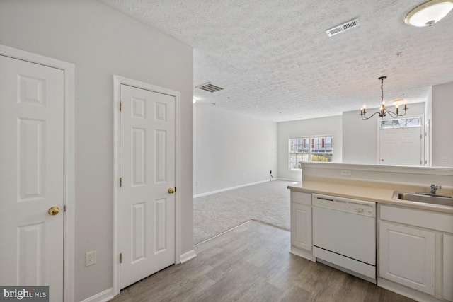 kitchen with a sink, a chandelier, dishwasher, baseboards, and visible vents