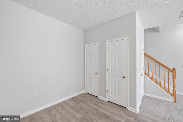 unfurnished bedroom with a textured ceiling, baseboards, and wood finished floors