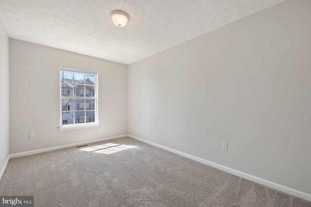 carpeted empty room with visible vents, baseboards, and a textured ceiling