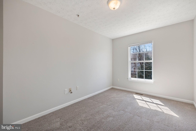 unfurnished room featuring baseboards, visible vents, carpet, and a textured ceiling
