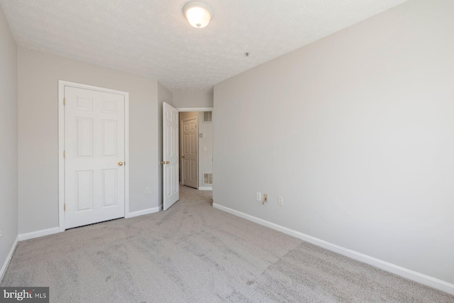unfurnished bedroom featuring baseboards, carpet flooring, a textured ceiling, and visible vents