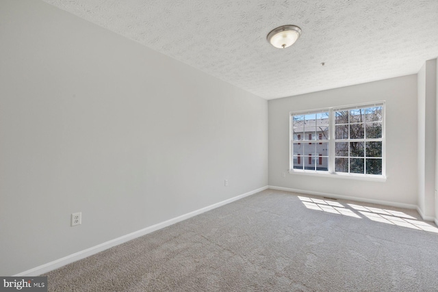 carpeted spare room with baseboards and a textured ceiling