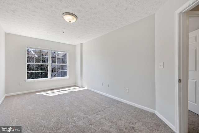 spare room with baseboards, carpet, and a textured ceiling