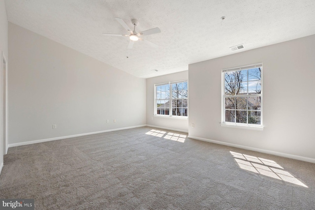 empty room with carpet, baseboards, a textured ceiling, visible vents, and a ceiling fan