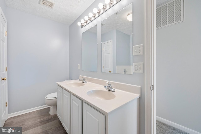 full bath with a sink, a textured ceiling, and visible vents