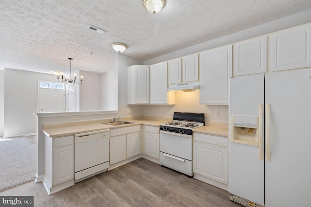kitchen featuring a sink, under cabinet range hood, white appliances, visible vents, and an inviting chandelier