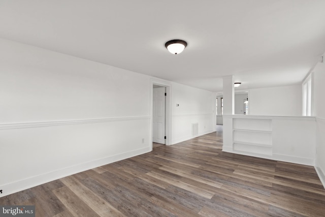 unfurnished room featuring baseboards, visible vents, and wood finished floors