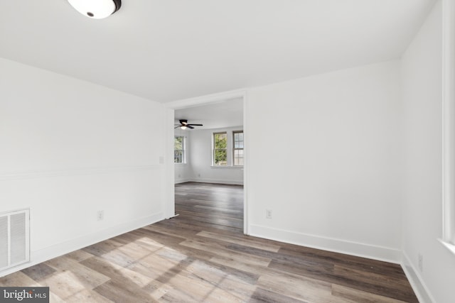 unfurnished room with wood finished floors, baseboards, ceiling fan, and visible vents