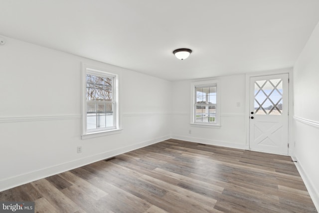entrance foyer featuring baseboards, visible vents, and wood finished floors
