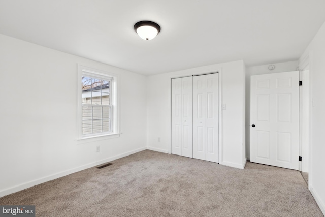 unfurnished bedroom featuring baseboards, visible vents, a closet, and carpet flooring