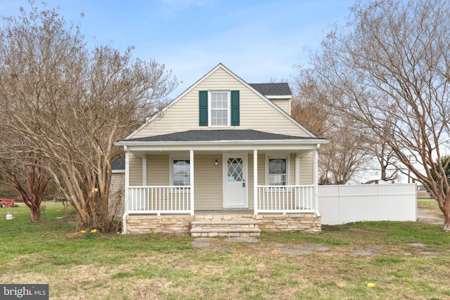 bungalow-style home with a front yard, a porch, and roof with shingles