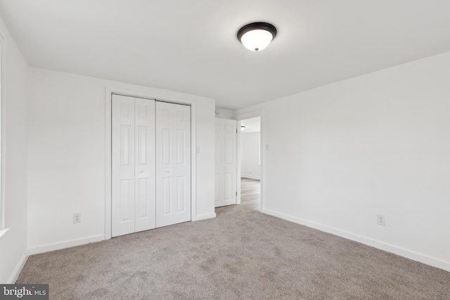 unfurnished bedroom featuring carpet floors, baseboards, and a closet