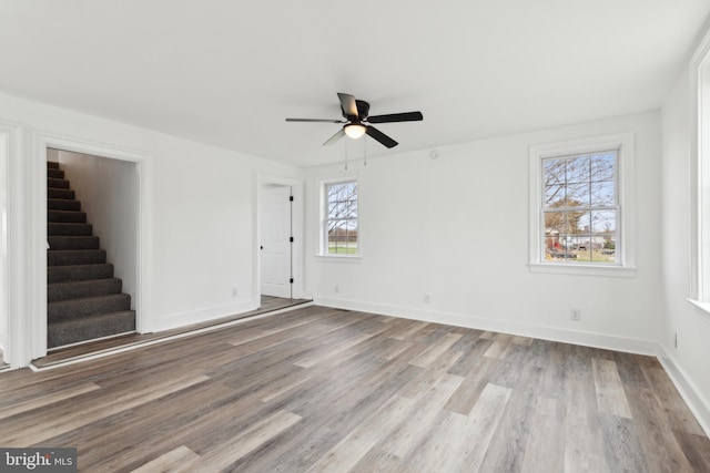 interior space featuring stairs, wood finished floors, baseboards, and a ceiling fan