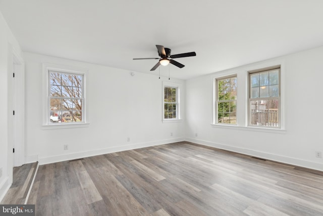 unfurnished room with baseboards, visible vents, wood finished floors, and a ceiling fan