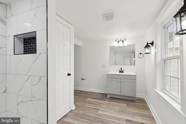 bathroom featuring vanity, baseboards, wood finished floors, and a notable chandelier