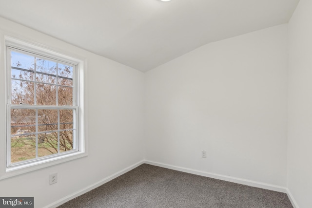 spare room with baseboards, lofted ceiling, and dark carpet