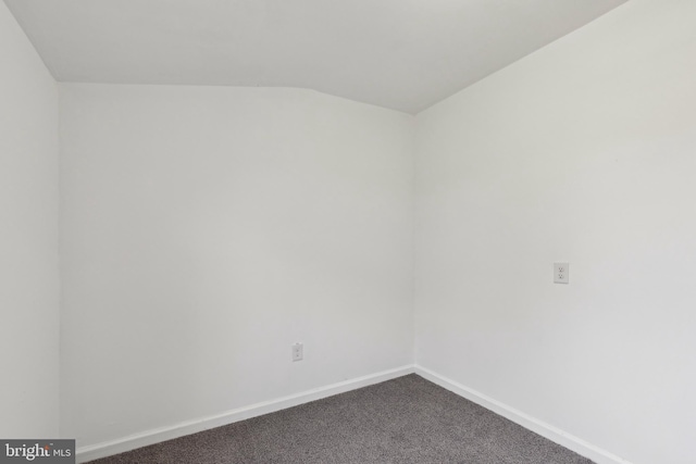 unfurnished room with baseboards and dark carpet