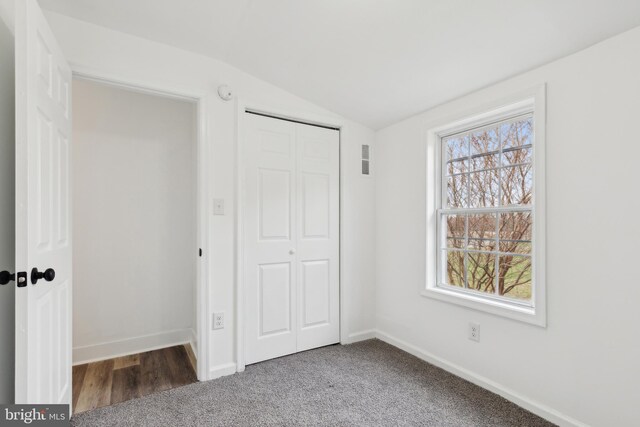 unfurnished bedroom featuring baseboards, a closet, vaulted ceiling, and visible vents