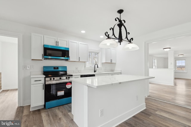 kitchen featuring a sink, stainless steel electric range, a center island, white cabinets, and light wood-style floors