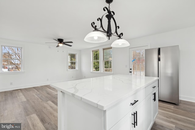 kitchen with freestanding refrigerator, hanging light fixtures, light stone countertops, and ceiling fan